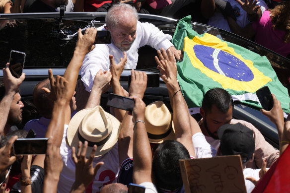 Luiz Inacio Lula da Silva holds hands with voters are he voted. 