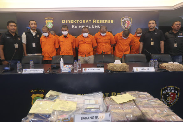 Indonesian police officers escort suspects and display the items of evidence during a press conference at Jakarta police headquarters.