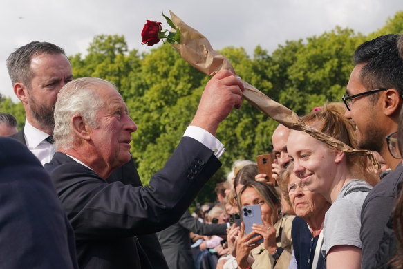 Charles accepts a rose from well-wishers during a walk outside Buckingham Palace.