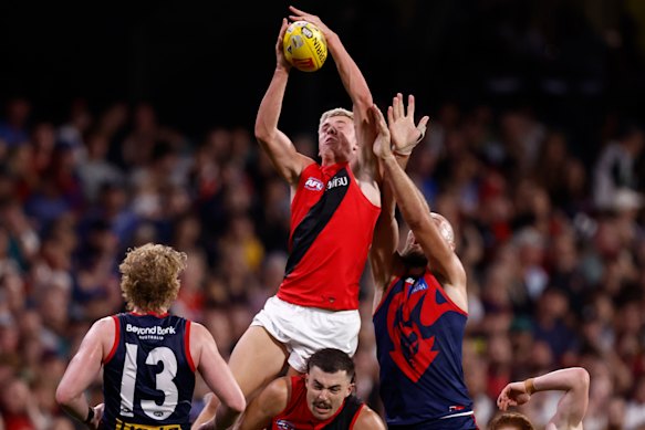 Nate Caddy of the Bombers attempts a high mark over Sam Draper of the Bombers and Max Gawn of the Demons.