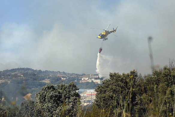 A firefighter helicopter dumping water on a fire in an industrial area of San Martin de Valdeiglesias, about 70 kilometres west of Madrid, on Sunday.