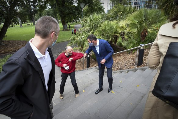 Victorian Premier Daniel Andrews is complimented by a passer-by after giving a Covid-19 update on the steps of Melbourne's Treasury Garden on Saturday. 