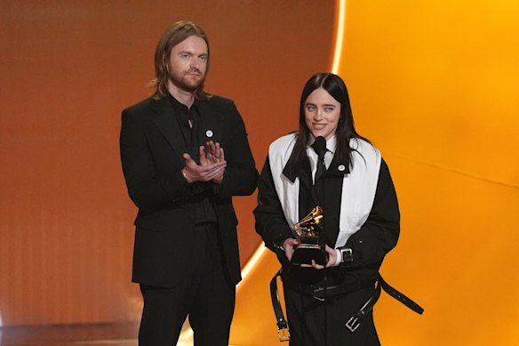Billie Eilish took aim at ICE while accepting the award for song of the year for Wildflower with brother Finneas O’Connell, left.