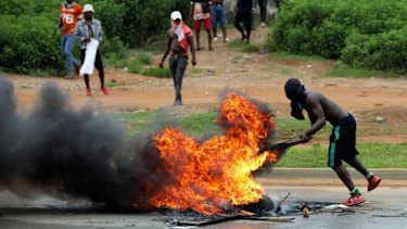 A man stands by a bonfire during a protest opposite a South African-owned  Shoprite in Abuja, Nigeria on Wednesday. 