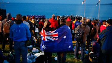 A pair draped with an Australian flag, participate in the Dawn Service ceremony at the Anzac Cove beach in Gallipoli, Turkey. 