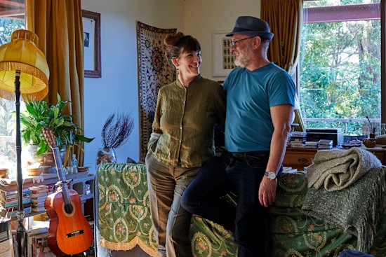 Kate Holden and Tim Flannery in the open-plan living area, where they like to entertain. It is filled with books, plants and numerous op-shop finds. Suspended above them is a wooden-framed canoe handcrafted by Peter Ingram-Jones.
