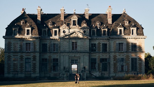 Tim Holding with his fiancée, Felicity Selkirk, and dog Truffe outside their 105-room 
fixer-upper.