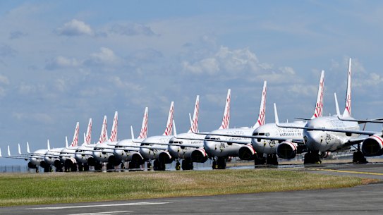 Grounded Virgin Australia aircraft are seen parked at Brisbane Airport in Brisbane, Tuesday, April 7, 2020. Brisbane Airport Corporation (BAC) is working with airlines by accommodating up to 100 grounded aircraft free of charge in response to government-mandated travel restrictions that have grounded a significant proportion of Australia's airline fleet because of the Coronavirus (COVID-19). (AAP Image/Darren England) NO ARCHIVING