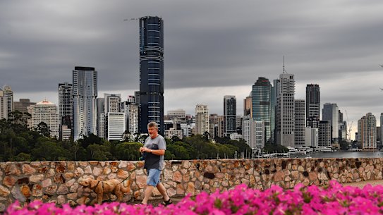 FILE IMAGE: A man walks his dog at the Kangaroo Point cliffs as storm clouds gather over the Brisbane CBD.