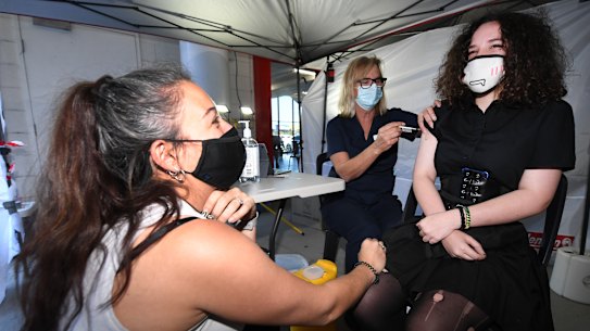 13 year-old Emily Connor (R) is supported by her mother as she receives a Covid-19 vaccine at a Bunnings hardware store.