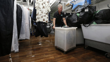 Gisbourne drycleaner Matthew Hyde attempts to move clothing off the floor of his shop after it was inundated with water. 