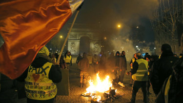 Demonstrators wearing yellow vests stands next to a burning bicycle at the Champs Elysees avenue during a protest in Paris on Saturday.