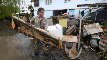 A man helps strangers remove flood-damaged items from their home in the Townsville suburb of Rosslea on Thursday.