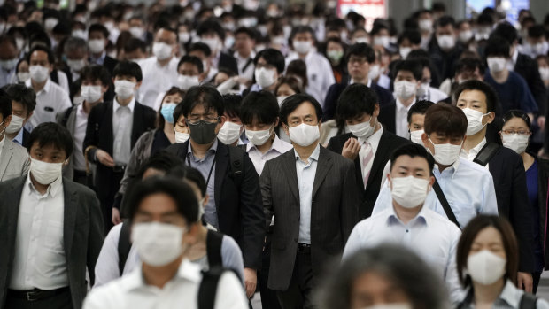 A station passageway is crowded with commuters wearing face mask during a rush hour in Tokyo, Japan.