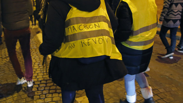 A police officer wears a yellow vest which reads 'good-bye Macron' during a rally to protest working conditions.