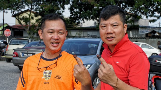 Alex Lum, left, and KC Yum holding up their inked fingers after voting in Selangor, Malaysia.