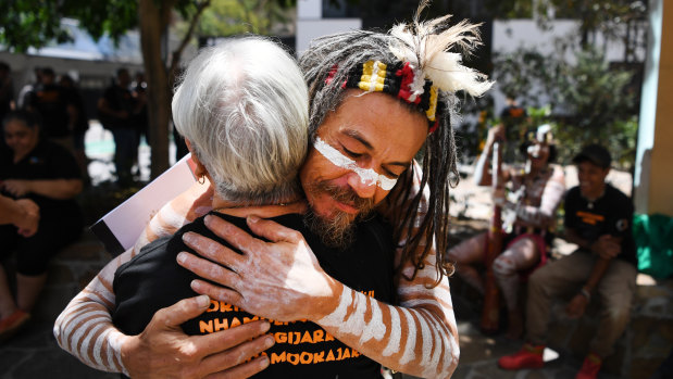 Traditional owner Joshua Walker hugs a supporter outside the Federal Court in Brisbane.