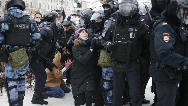 Police detain a man as another policeman stops a young woman, center, during a protest against the jailing of opposition leader Alexei Navalny in Moscow, Russia. 