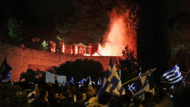 A flare thrown by opponents of Prespa Agreement, attending a rally outside the Greek Parliament, burns in front of police officers in Athens on Thursday.