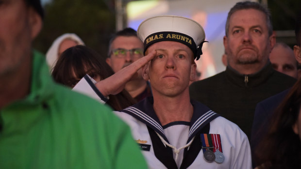 Serviceman Nick Dent salutes as the Australian national anthem is played during the ceremony. 