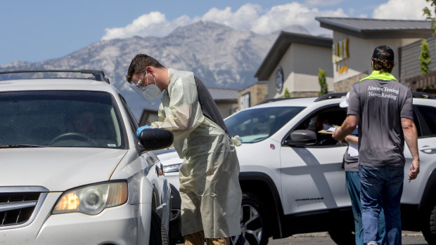 A healthcare worker administers a COVID-19 test at a Utah County Health Department drive-through testing site in American Fork, Utah. 