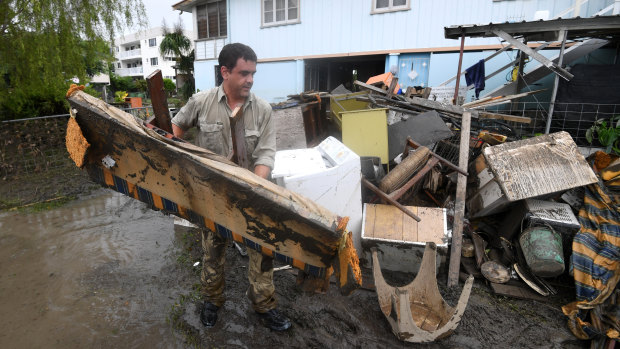 A man helps strangers remove flood-damaged items from their home in the Townsville suburb of Rosslea on Thursday.