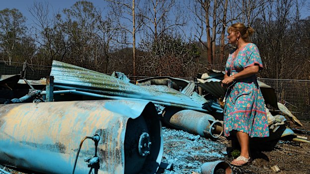 Kim McDonald assesses the remains of her home which was sprayed with a glue-like substance to stick down any possible asbestos fibres.