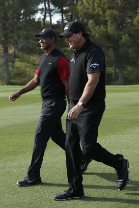 All smiles: Phil Mickelson and Tiger Woods laugh as they walk up the second fairway during a golf match at Shadow Creek.