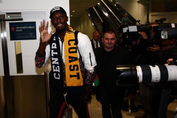 Usain Bolt waves to fans as he walks through Sydney Airport.