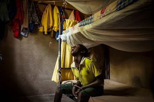David, 18, sits with his hands bound by rope to the bunk bed. David lives with an intellectual disability.