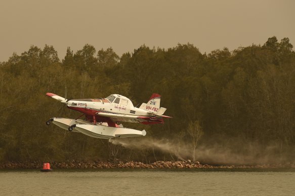 A seaplane loads water in the Moruya River to tackle fires to the north of Moruya on the NSW South Coast. 
