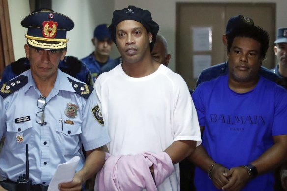 Former soccer star Ronaldinho, second from left, and his brother Roberto de Assis Moreira walks escorted by police officers to declare to judge Clara Ruiz Diaz at Justice Palace in Asuncion, Paraguay. 