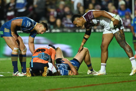 Shaun Lane receives treatment after a tackle from Haumole Olakau’atu and Daly Cherry-Evans.