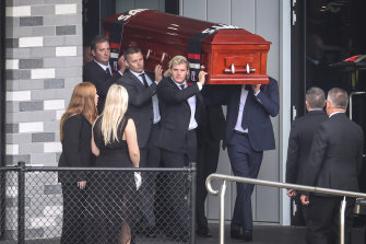 Shane Warne’s daughters, Summer (left) and Brooke, watch as his son Jackson (front) helps carry the coffin onto Moorabbin Oval. 