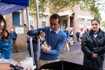 Dave Sharma tucks into a bacon and egg roll after voting in Paddington.
