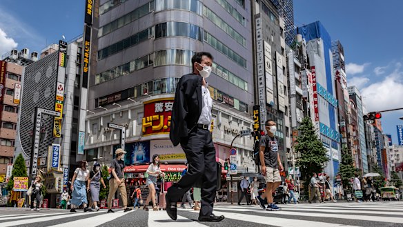 A masked-up Tokyo goes about its daily business. Community infections, unrelated to the Games, have surged.