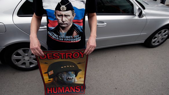 A man wearing a shirt showing a picture of Russian President Vladimir Putin holds an anti NATO poster during a protest outside the Syrian embassy in Belgrade, Serbia, on Sunday.