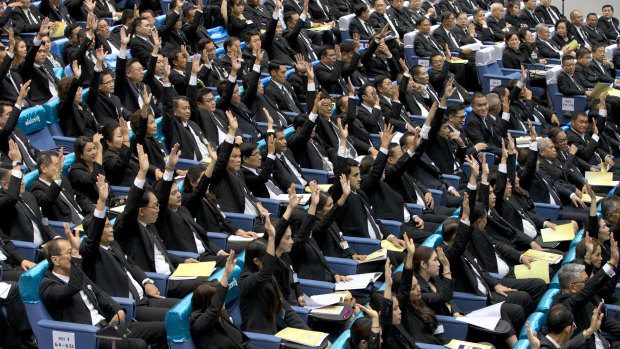 Members of the parliament representing military-backed Palang Pracharath party raise their hands approving the nomination of Prayuth Chan-ocha as Thailand's Prime Minister on Wednesday .