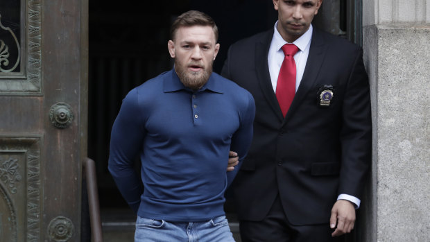 A handcuffed Conor McGregor is escourted from a New York police station on Friday after being arrested for attacking a bus of UFC rivals. 