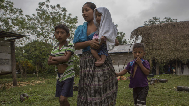 Claudia Maquin, 27, walks with her three children outside her father-in-law's house in Raxruha, Guatemala.