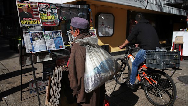 A man reads the front pages of newspapers showing the news the Mexican President Andres Manuel Lopez Obrador has COVID-19, at a kiosk on Paseo de la Reforma in Mexico City.