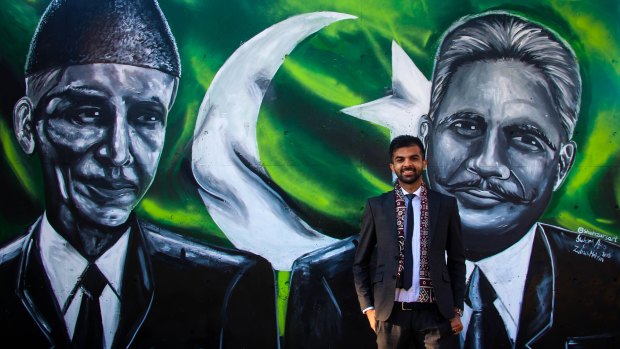 Artist Shehzar Abro alongside the mural he painted of Muhammad Ali Jinnah and Allama Iqbal on the façade of the Pakistan High Commission in Canberra.