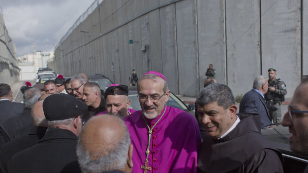 Archbishop Pierbattista Pizzaballa, the top Roman Catholic cleric in the Holy Land, center, is received by worshippers while his convoy crosses an Israeli military checkpoint from Jerusalem.