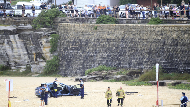 Emergency services survey the wreckage after a car plunged several meters over an embankment.