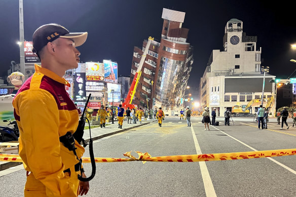 A rescue worker stands near the cordoned off site of a leaning building in the aftermath of an earthquake in Hualien, eastern Taiwan.