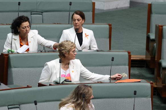 Zali Steggall places a floral tribute at Helen Haines’ empty seat. Steggall is also wearing an orange pin (orange is Haines’ campaign colour).
