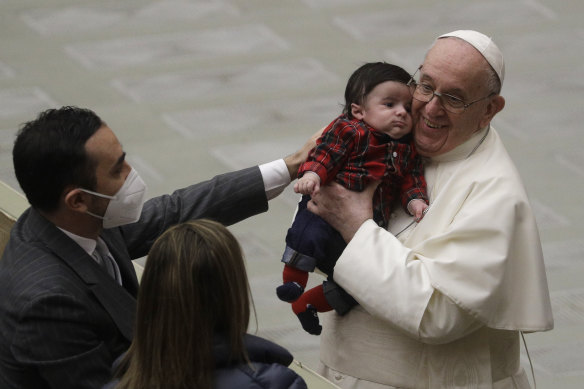 Pope Francis embraces the child of a Vatican employee in the Paul VI hall , Monday, Dec. 21, 2020. 