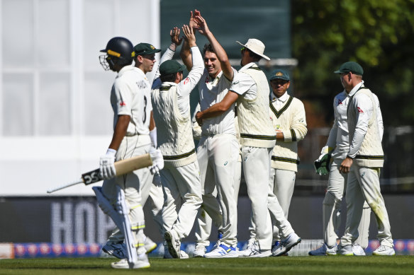 Australia’s Pat Cummins, centre, celebrates with teammates after taking the wicket of New Zealand’s Rachin Ravindra. 