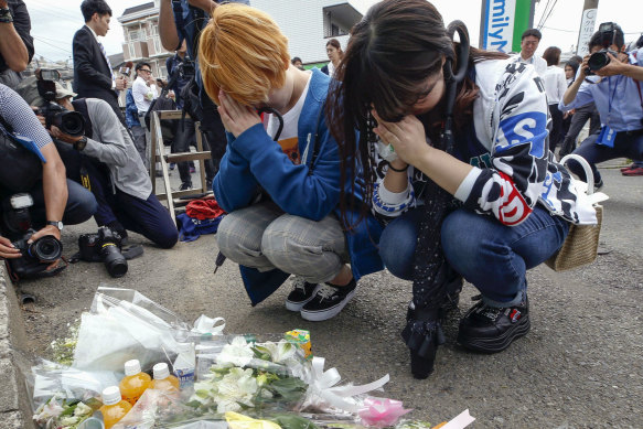 Women pray after offering flowers near the scene where a man carrying a knife in each hand and screaming "I will kill you!" attacked a group of schoolgirls and adults as he walked toward a bus stop just outside Tokyo.