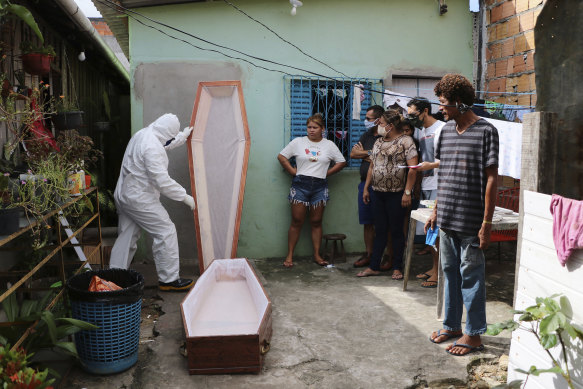 A funeral worker wearing protective gear prepares a coffin for 86-year-old Raimundo Costa do Nascimento, who died at home in Manaus during the coronavirus pandemic.